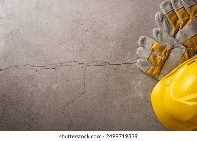 Image depicting a Labor Day concept with a yellow hard hat and work gloves placed on a cracked concrete surface - Powered by Shutterstock