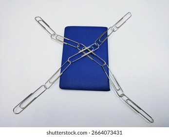 The image depicts a blue, rectangular object, resembling a visa card holder lying flat on a white surface. Overlaid on this object is a chain formed an X cross shaped giving it locked theme