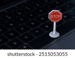 The image depicts a stop sign placed on a laptop keyboard, symbolizing the need to pause or halt online activity.