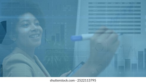Image of diagrams and data processing over biracial businesswoman taking notes. Global business and digital interface concept digitally generated image.