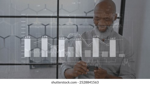 Image of diagrams and data processing over biracial businessman using smartphone. Global business, technology and digital interface concept digitally generated image.