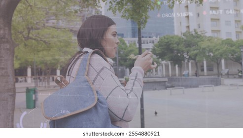 Image of diagrams and data processing over caucasian woman walking and eating in city. Business, technology and digital interface concept digitally generated image. - Powered by Shutterstock