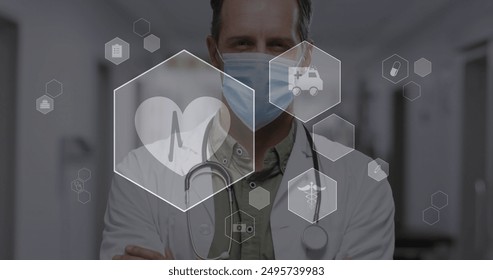 Image of digital icons data processing over caucasian male doctor in face mask. Global medicine, computing, digital interface and data processing concept digitally generated image.