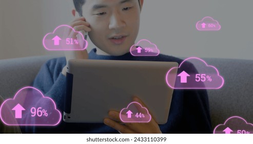 Image of digital interface with pink cloud icons and numbers growing over man talking on smartphone holding digital tablet. Global computer network technology concept digitally generated image.