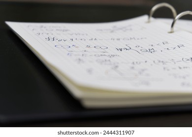 The image displays a notebook filled with complex mathematical equations and diagrams, written in blue and red ink, highlighting a detailed study or problem-solving session.
 - Powered by Shutterstock