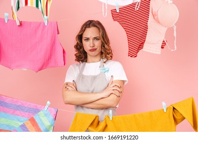 Image Of Displeased Sad Woman Housewife Isolated Over Pink Wall Background Dry Clothes On Rope.