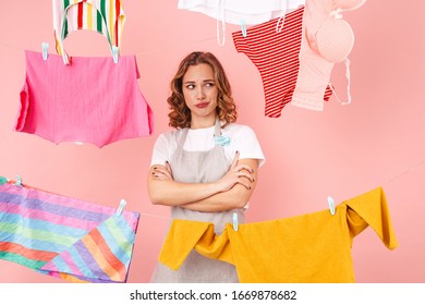 Image Of Displeased Sad Woman Housewife Isolated Over Pink Wall Background Dry Clothes On Rope.