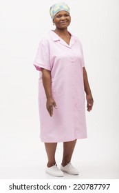 Image Of A Domestic Worker In Her Work Uniform Standing With Her Hands At Her Sides And Smiling