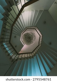 An image of a dramatic, worm's-eye view looking directly up the center of a spiral staircase.