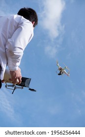 Image of a drone pilot piloting with the controller in hand and watching the drone fly over him, during a flight practice at a pilot school