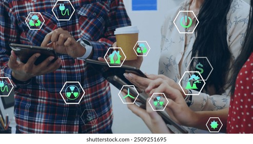 Image of ecology icons over diverse colleagues using tablet in office. Business, technology and digital interface concept digitally generated image. - Powered by Shutterstock