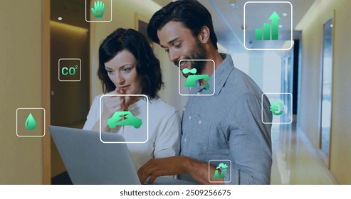 Image of ecology icons over diverse colleagues using laptop in office. Business, technology and digital interface concept digitally generated image. - Powered by Shutterstock