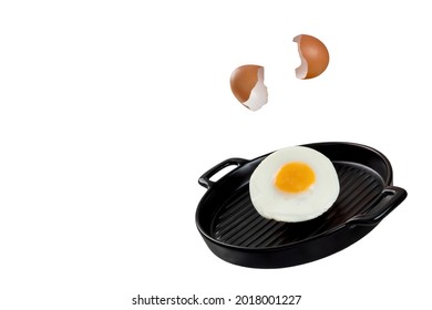 An image of an egg being cracked, falling, and transforming to fried egg on a black ceramic serving pan. Levitation food concept. 
