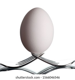 Image of an egg placed on two forks isolated on black background