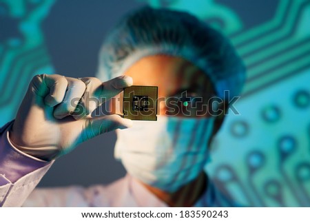 Image of an electronic engineer analyzing computer microchip holding on the foreground 