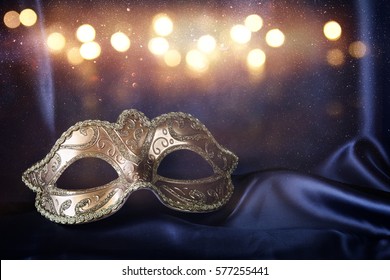Image of elegant gold venetian mask on blue silk background