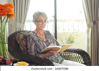 Image Of An Elegant Senior Lady Sitting In An Armchair And Reading A Book