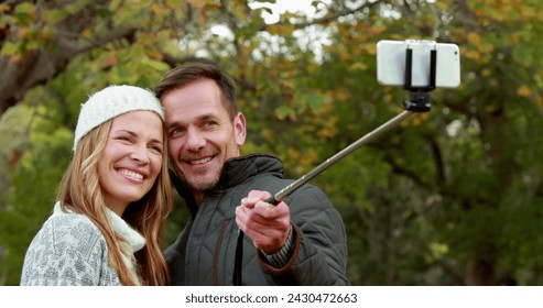 Image of emoji icons flying up with a young Caucasian couple taking a selfie with a selfie stick in a park in the background 4k