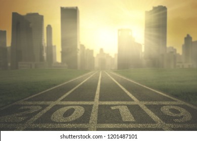 Image of an empty asphalt track with number 2019 toward modern city at sunrise time