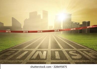 Image of an empty finish line with numbers 2016 on the tape and bright sun rays at the end of track