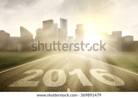 Image of empty highway with numbers 2016 and bright sunlight toward the city