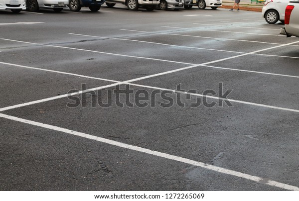 Image of empty parking spaces on\
asphalt ground of parking area after raining in the\
evening.