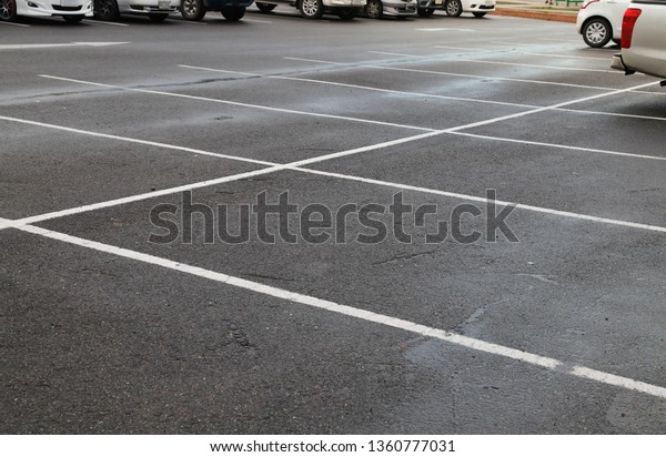 Image of empty parking\
spaces on asphalt ground of parking area after raining in twilight\
evening.