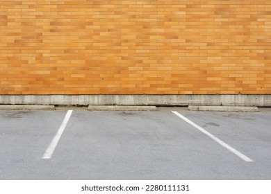 An image of an empty parking spot in front of a reddish brown brick wall. 