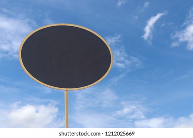 Image of empty small chalkboard display ellipse label on blue sky with cloud background. Mock-up of menu blackboard.
