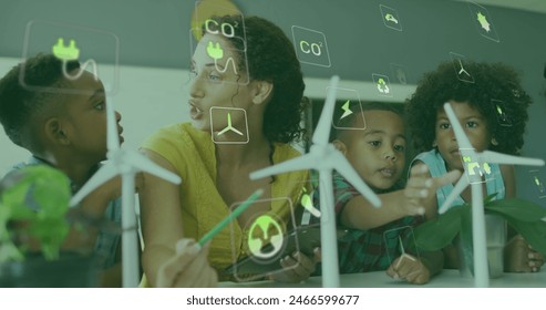 Image of energy icons over happy diverse female teacher and pupils with wind turbines in class. Ecology, resources, school, childhood, education and learning, digitally generated image. - Powered by Shutterstock