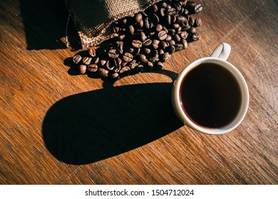 image of an espresso surrounded by coffee beans coming out of a hessian sack with shadows featuring due to bright conditions from a window