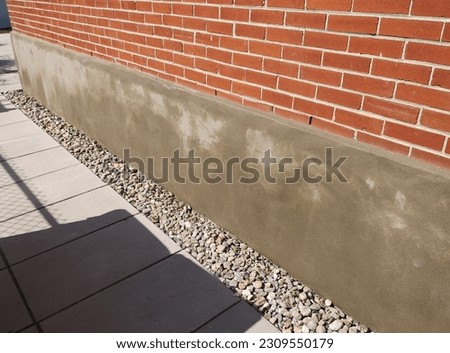 Image example of a newly applied sponge finish cement parging application on an exterior concrete foundation wall in the process of curing.
