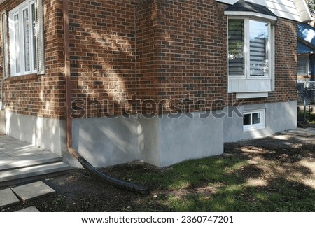 Image example showing a fresh cement parging exterior application layer after the first few days of the curing process. Thin two-coat layer on the foundation of a brick facade house.