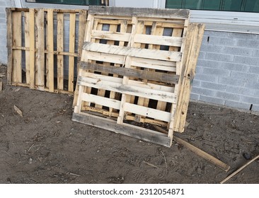 Image example showing a pile of standing wooden pallets leaning against an exterior commercial building brick wall. - Shutterstock ID 2312054871