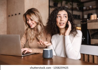 Bild von aufgeregten Freunden emotionaler Mädchen, die im Café sitzen und Laptop-Computer telefonieren.
