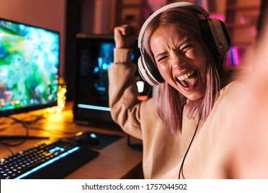 Image Of Excited Girl Taking Selfie Photo And Making Winner Gesture While Playing Video Game On Computer Indoors