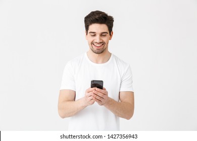 Image Of Excited Happy Young Man Posing Isolated Over White Wall Background Using Mobile Phone.