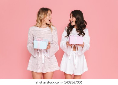 Image Of Excited Happy Young Two Pretty Women Girls Friends Sisters Posing Isolated Over Pink Wall Background Holding Present Boxes.