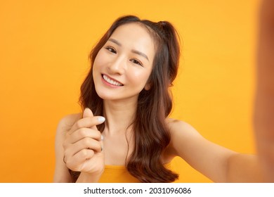 Image of excited happy young woman isolated over yellow background make selfie by camera.
