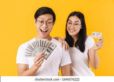 Image of excited multinational couple showing dollars and credit card isolated over yellow background - Shutterstock ID 1696576222