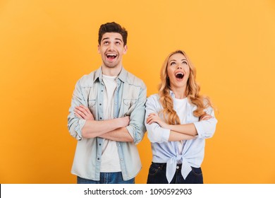 Image of excited people man and woman in basic clothing posing with arms crossed and looking upward isolated over yellow background - Shutterstock ID 1090592903