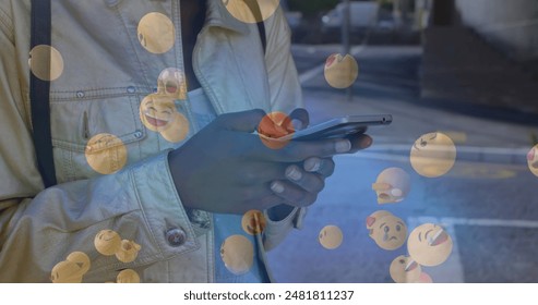 Image of falling emoji over african american woman using smartphone. social media and communication concept digitally generated image. - Powered by Shutterstock