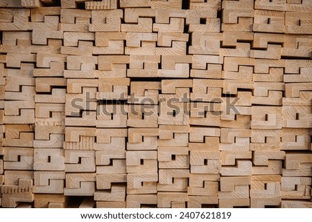 The image features a close-up view of a stack of wooden beams with a unique interlocking pattern.