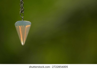 The image features a lovely opalite pendulum with a silver chain, positioned on the right side, leaving ample copy space.
