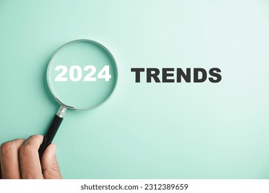 The image features magnifier glasses with the text New Year 2024 Trends, emphasizing the main trend of change. It represents the evaluation methods, popular topics, and new trends in business.
