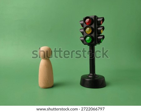 The image features a mini traffic light toy and a wooden peg doll on a green background.