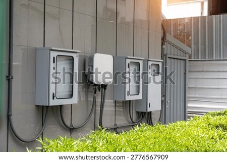 The image features modern utility boxes and meter devices mounted on an exterior wall, part of an electrical infrastructure setup for power distribution and monitoring.