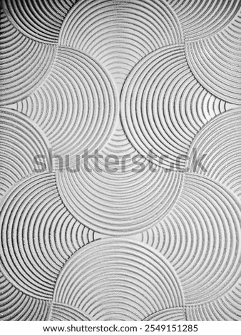 The image features a textured background with overlapping circular patterns. Each circle is detailed with concentric grooves, creating a geometric and tactile visual effect in grayscale tones.