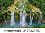 The image features a waterfall with a green and brown hue, surrounded by a lush forest with a lot of trees and foliage. This image location is Tamul waterfall in the state of San Luis Potosí, Mexico.