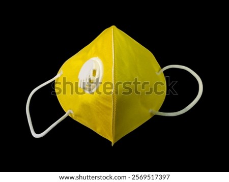 The image features a yellow object, specifically an N95 mask designed for protection against PM 2.5 particles.The mask is intended to provide a secure fit and filter out harmful pollutants effectively